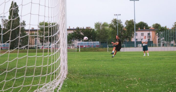 Joueur de football frappant le ballon vers le but sur un terrain en pelouse